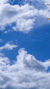 a blue sky with white clouds and a plane flying through it