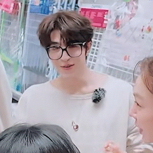 a man wearing glasses and a white sweater is standing next to a woman .