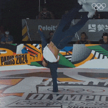 a man is doing a handstand in front of a paris 2024 sign