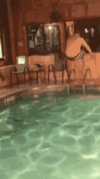 a man is jumping into a swimming pool with a ladder