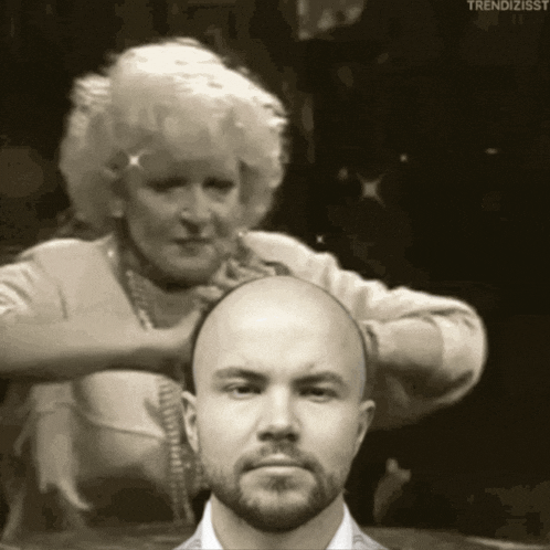 a man with a beard is getting his hair cut by a woman