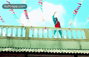 a man is standing on a balcony with his arms up in the air