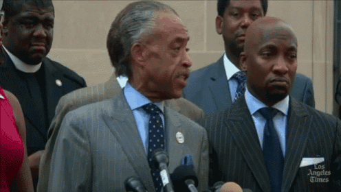a man in a suit and tie is speaking into a microphone with the los angeles times written on the bottom