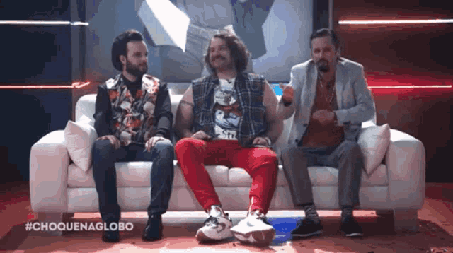 three men are sitting on a white couch with the hashtag #chouenaglobo