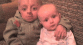 two babies are sitting next to each other on a couch