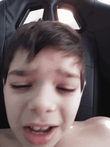 a young boy without a shirt is making a funny face