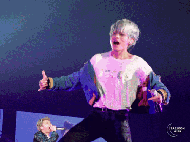 a man singing into a microphone with taejoon gifs written on the bottom right corner