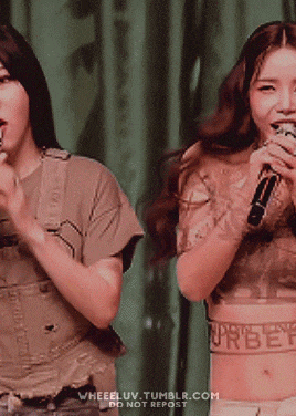 two women singing into microphones with the words burberry on their waists