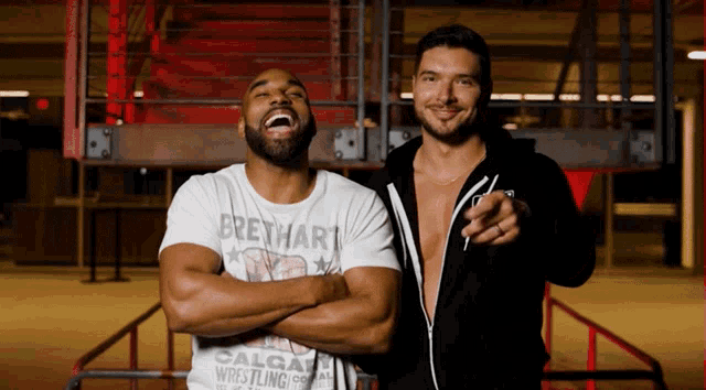 two men standing next to each other with one wearing a calgary wrestling company shirt