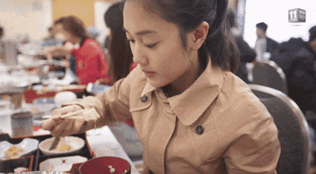 a woman is sitting at a table eating food with a sign that says 11 on it