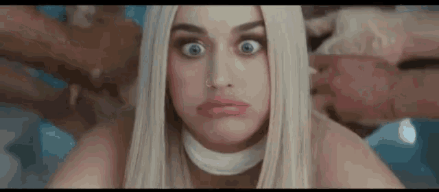 a close up of a woman making a funny face while being held by a group of people .