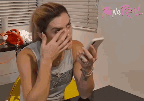 a woman covering her mouth while looking at a cell phone with the words provas meu amor written below her