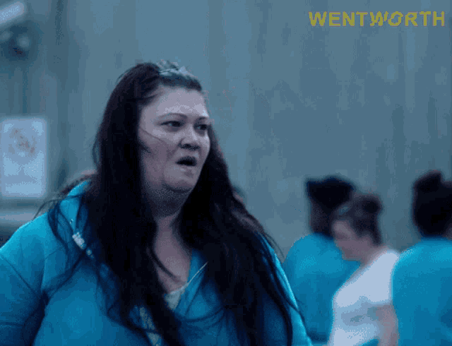 a woman in a blue jacket is standing in front of a sign that says " wentworth "