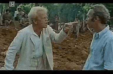 two men are standing next to each other and one of them is pointing at the other .