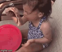 a little girl is eating a piece of pizza next to a red plate