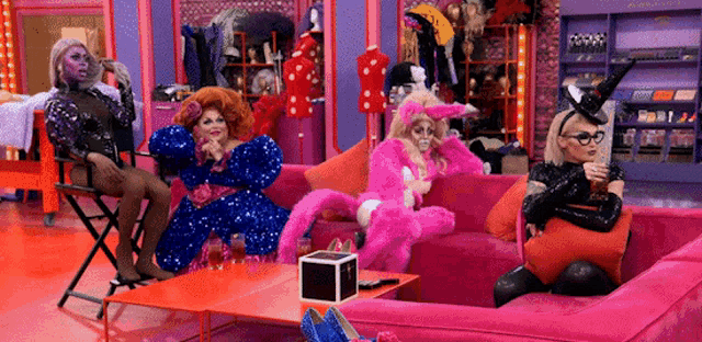 a group of drag queens are sitting on a couch