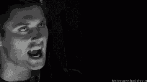 a black and white photo of a man 's face with a mustache in the dark .