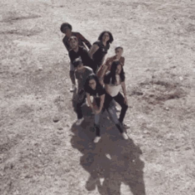 a group of people are posing for a picture on a dirt field