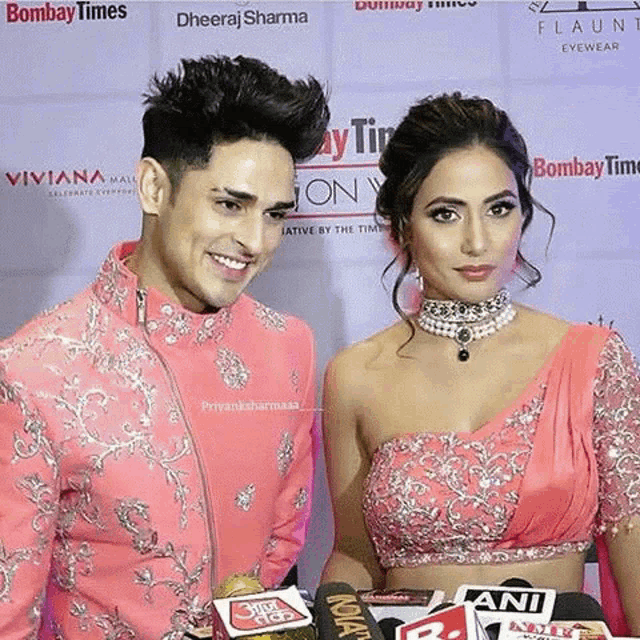 a man and a woman are standing next to each other on a red carpet and smiling .