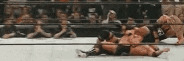 two men are wrestling in a ring with a crowd watching .
