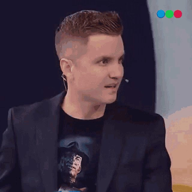a man wearing a freddy krueger shirt and a suit talks into a microphone