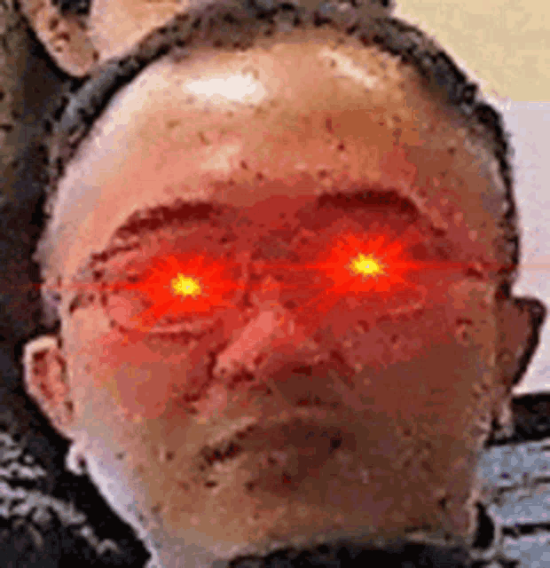 a man with red eyes and glasses is looking at the camera .
