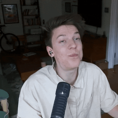 a young man wearing earbuds and a microphone looks at the camera