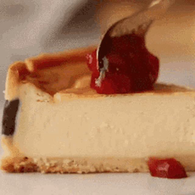 a slice of cheesecake with a spoon of cherry sauce on top