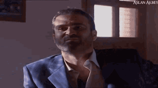 a man in a suit and tie with aslan akbey on the bottom right