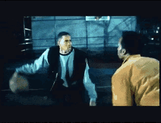 a man in a yellow jacket is playing basketball with a man in a green sweater