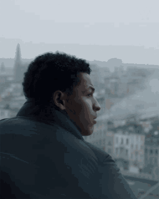 a man looking out a window with a v on the bottom right