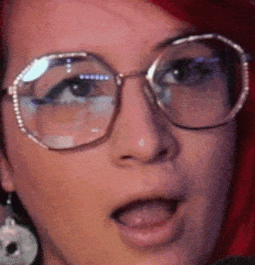 a close up of a woman wearing glasses with her tongue hanging out .