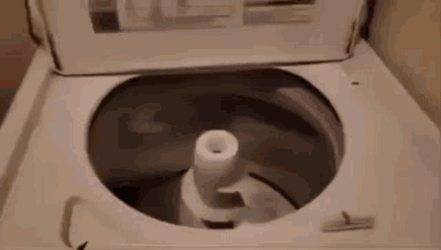a close up of a washing machine with the lid open and clothes in the washer .