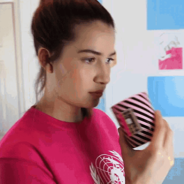 a woman in a pink shirt holds a pink and black striped item