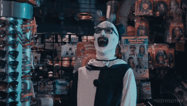 a man in a clown costume is standing in front of a display of face booth items