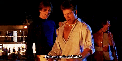 a man in a white shirt is standing next to another man and saying welcome to the o.c bitch .