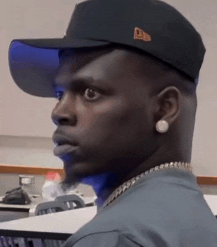 a man wearing a hat and earring looks to the side