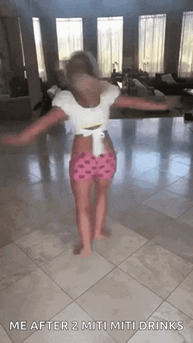 a little girl is dancing in a living room with the words me after 2 miti miti drinks on the bottom