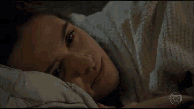 a woman laying in bed with her hand on her forehead and a circle in the corner