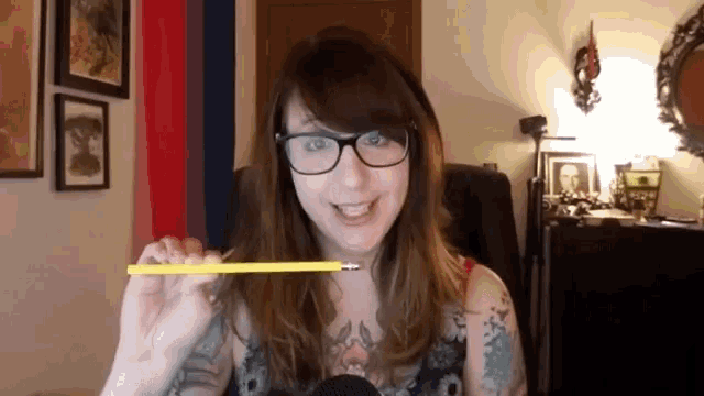 a woman with glasses holds a yellow pencil in her hand