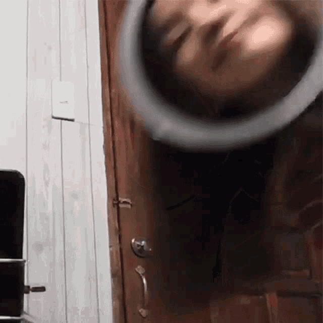 a woman 's head is sticking out of a wooden door