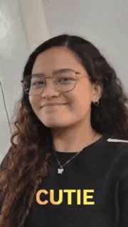 a woman wearing glasses and a black shirt with the word cutie written on it .