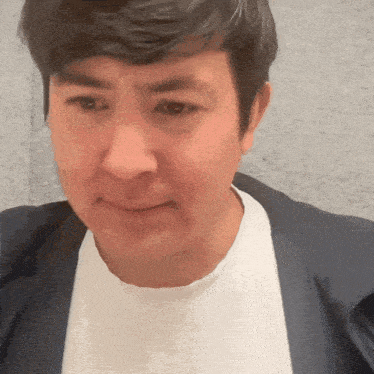 a man wearing a white shirt and a blue jacket making a funny face