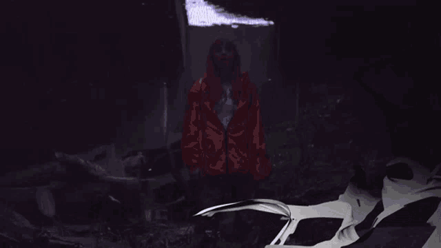 a man in a red jacket stands next to a white car