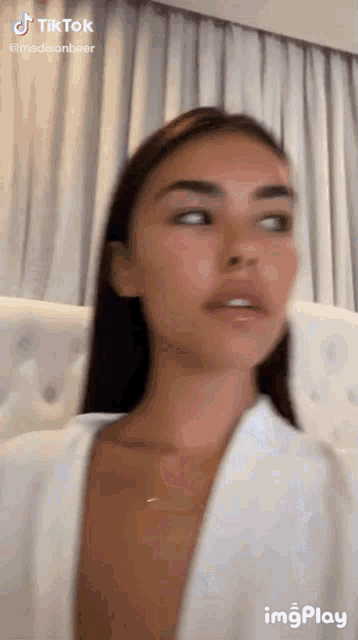 a woman is sitting on a bed in front of a white curtain .