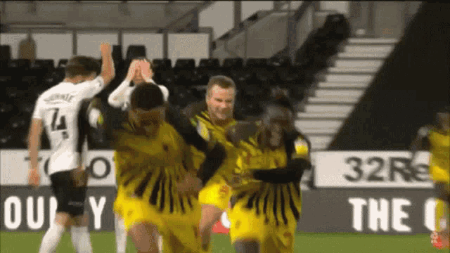 a group of soccer players are celebrating a goal in front of a sign that says 32r