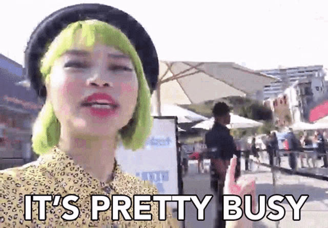 a woman with green hair says it 's pretty busy in front of a crowd