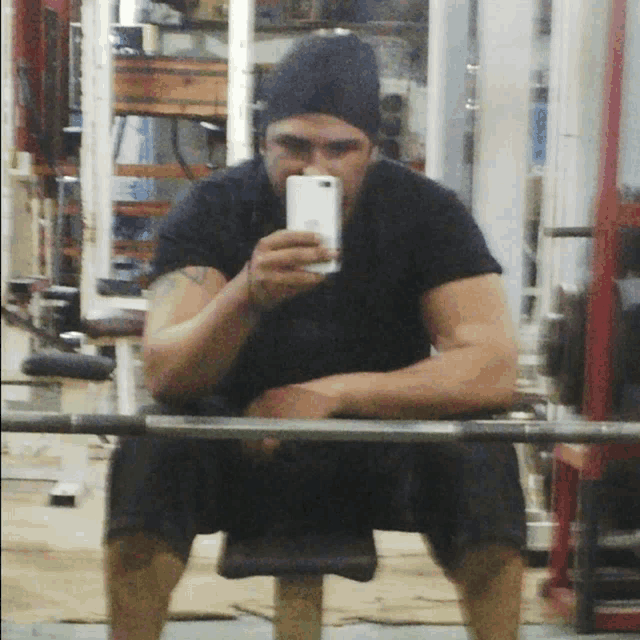a man taking a selfie in a gym with his phone