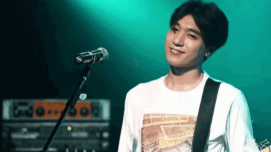a young man is singing into a microphone on a stage .