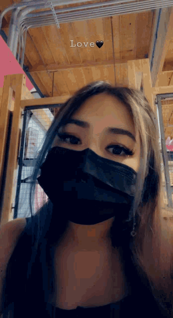 a woman wearing a black face mask has the word love above her head